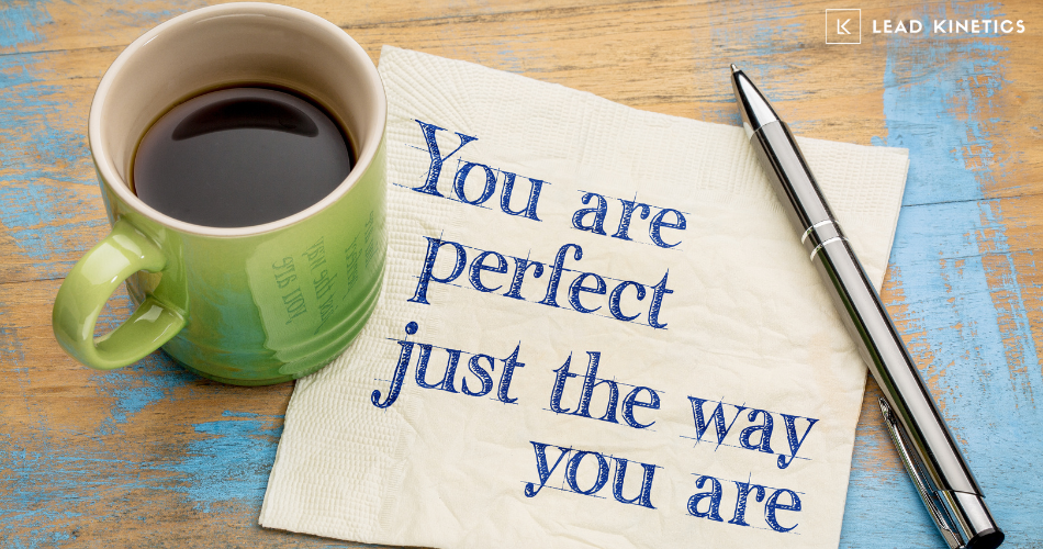 Coffee cup, pen, and napkin with handwritten message reading "You are perfect just the way you are" — styled with a positive and motivational tone, set on a rustic wooden background.